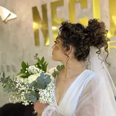 Noiva de perfil com penteado cacheado e véu, logo Nego Hair ao fundo