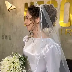 Noiva com tiara e véu sorrindo, letreiro Nego Hair ao fundo