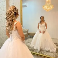 Noiva se olhando no espelho de moldura dourada, penteado com curls